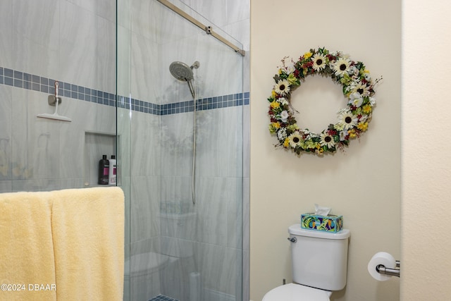 bathroom featuring toilet and a shower with door