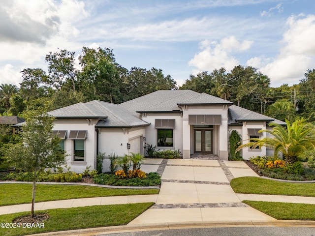 prairie-style home with a front lawn, a garage, and french doors