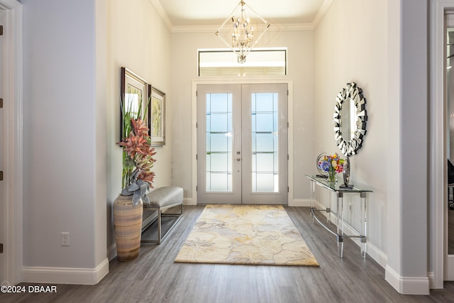 foyer entrance with french doors, wood-type flooring, a notable chandelier, and ornamental molding