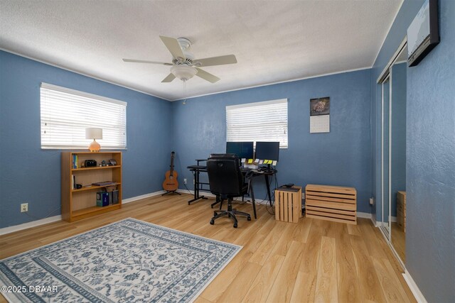 home office featuring a ceiling fan, wood finished floors, baseboards, and a textured wall