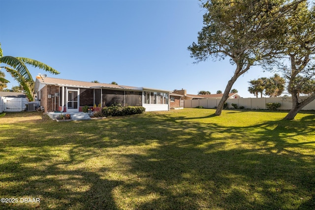 view of yard with central AC unit, a fenced backyard, and a sunroom