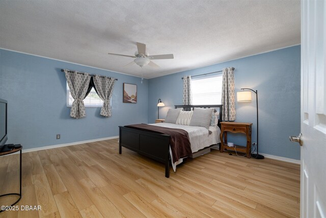 bedroom featuring light wood-style flooring, a textured ceiling, baseboards, and ceiling fan