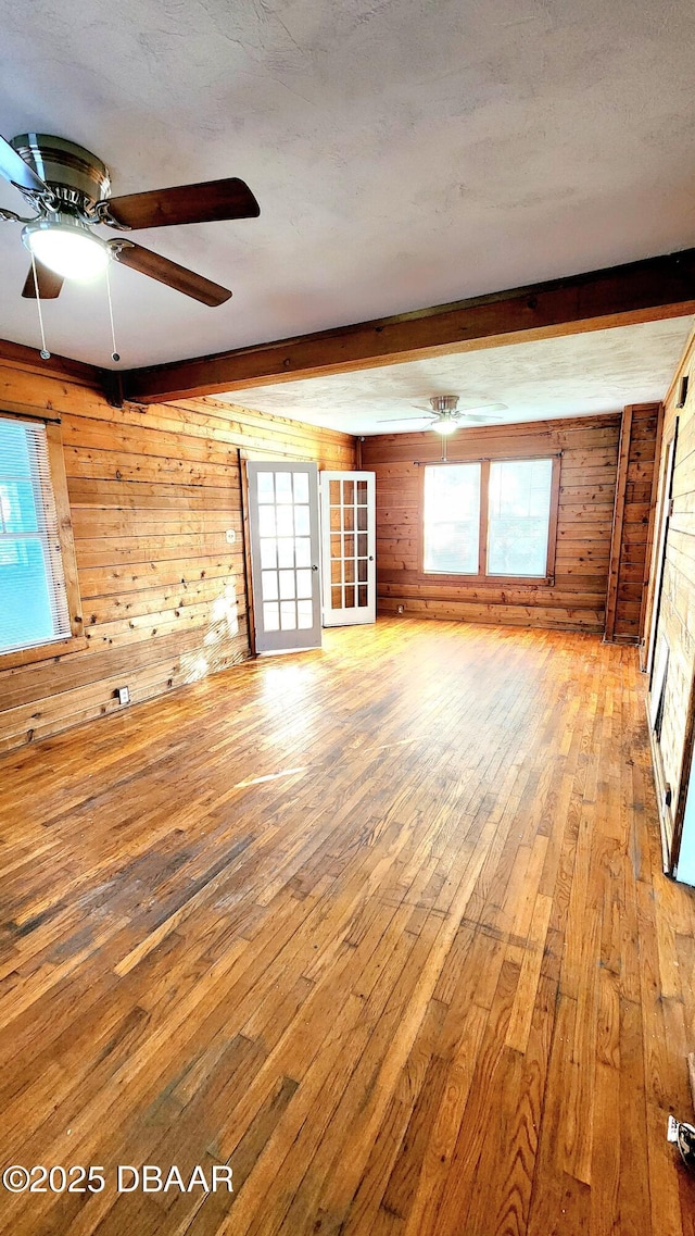 524 W St, Daytona Beach, FL 32114 - unfurnished living room with wood walls, wood-type flooring, beam ceiling, a ceiling fan, and healthy amount of natural light