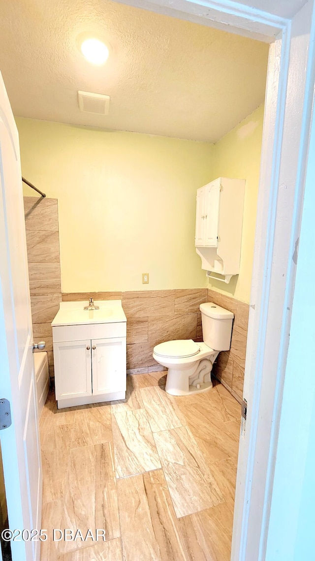524 W St, Daytona Beach, FL 32114 - full bathroom featuring toilet, vanity, a textured ceiling, and bathing tub / shower combination