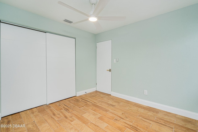 unfurnished bedroom featuring ceiling fan, a closet, and hardwood / wood-style flooring