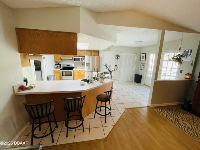3565 E Lake Dr, Land Olakes, FL 34639 - kitchen featuring appliances with stainless steel finishes, a sink, a kitchen breakfast bar, light countertops, and light tile patterned floors