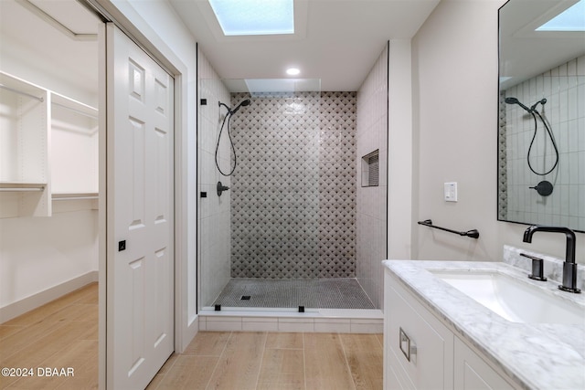 bathroom with a tile shower, vanity, and a skylight