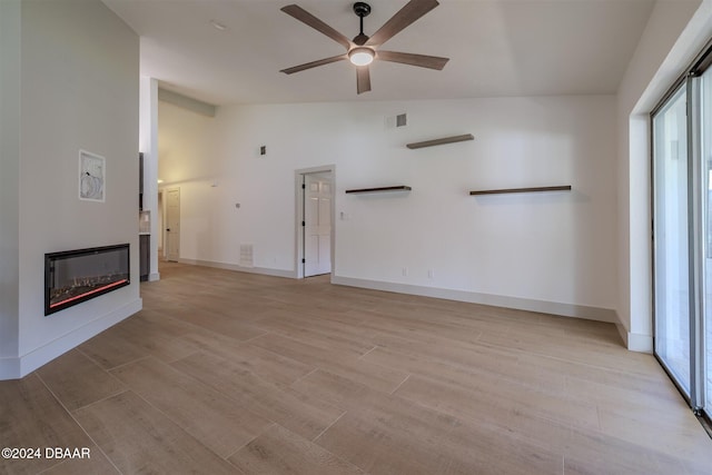 unfurnished living room featuring light hardwood / wood-style flooring, lofted ceiling, and ceiling fan