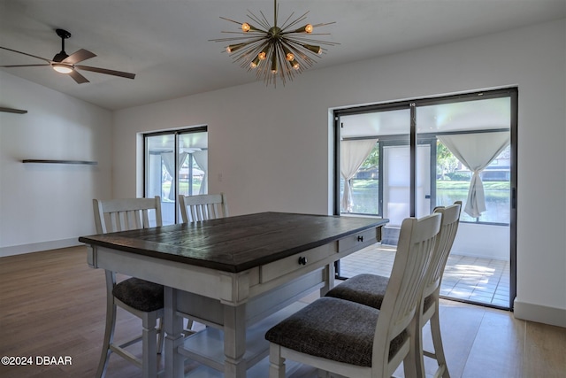 dining room with ceiling fan with notable chandelier, plenty of natural light, and light hardwood / wood-style flooring