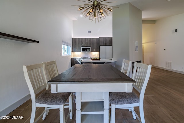 dining room with a towering ceiling, dark hardwood / wood-style flooring, and a notable chandelier