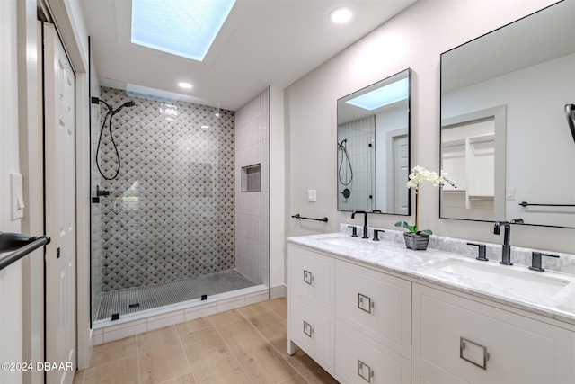 bathroom with hardwood / wood-style flooring, vanity, tiled shower, and a skylight