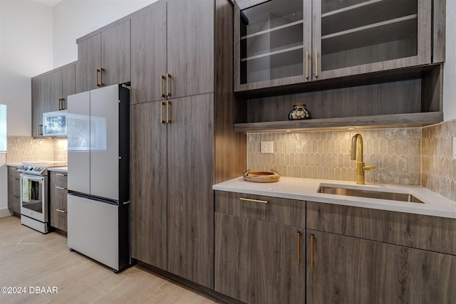 kitchen featuring tasteful backsplash, light wood-type flooring, dark brown cabinets, sink, and white appliances