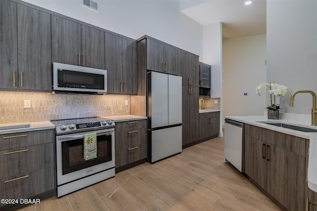 kitchen featuring dark brown cabinetry, appliances with stainless steel finishes, sink, and light hardwood / wood-style flooring