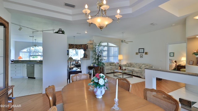 dining room featuring a raised ceiling, ceiling fan with notable chandelier, and light hardwood / wood-style flooring