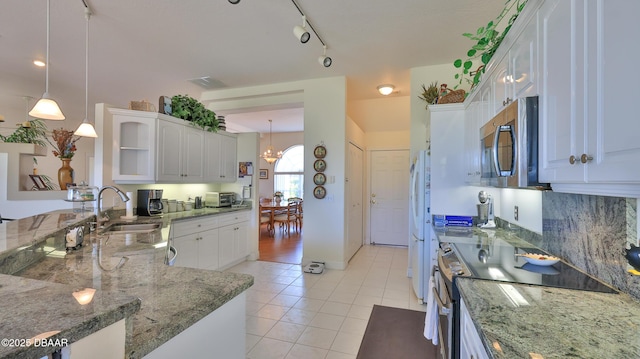 kitchen featuring pendant lighting, sink, dark stone countertops, white cabinets, and stove