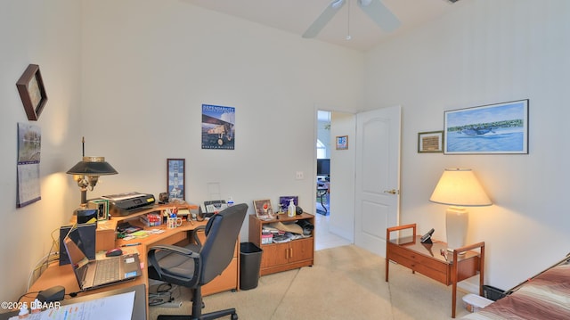 carpeted home office featuring a towering ceiling and ceiling fan