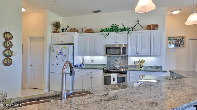 kitchen with sink, white cabinets, hanging light fixtures, light stone counters, and stainless steel appliances