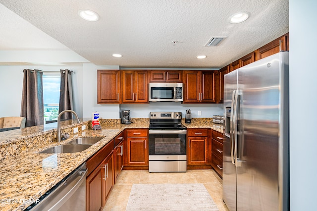 kitchen with light stone countertops, appliances with stainless steel finishes, a textured ceiling, sink, and light tile patterned floors