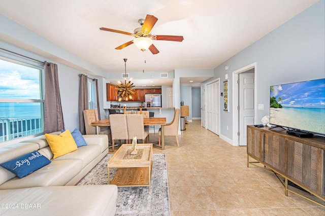 living room featuring ceiling fan with notable chandelier and light tile patterned flooring