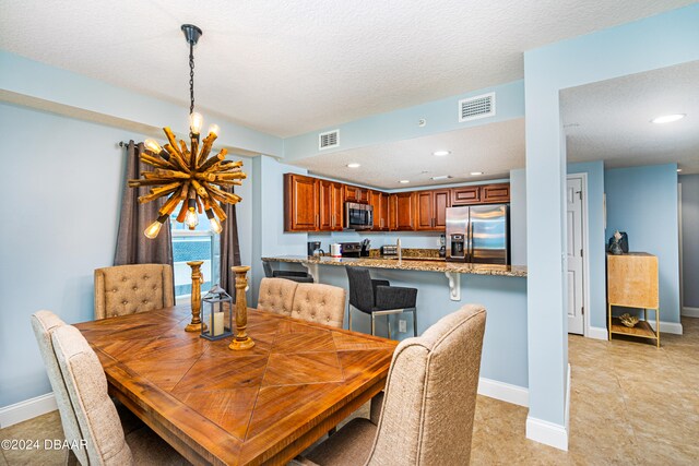 dining room featuring a notable chandelier, light tile patterned floors, and a textured ceiling