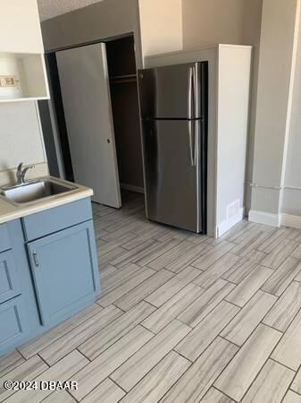 800 N Atlantic Ave Unit 508, Daytona Beach, FL 32118 - kitchen featuring freestanding refrigerator, a sink, wood tiled floors, blue cabinets, and open shelves