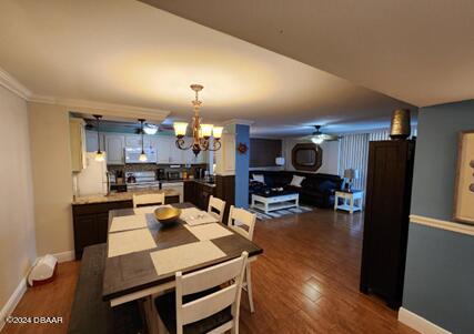 dining area with ornamental molding, dark hardwood / wood-style floors, and ceiling fan with notable chandelier