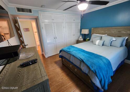 bedroom featuring a closet, ceiling fan, hardwood / wood-style flooring, and ornamental molding