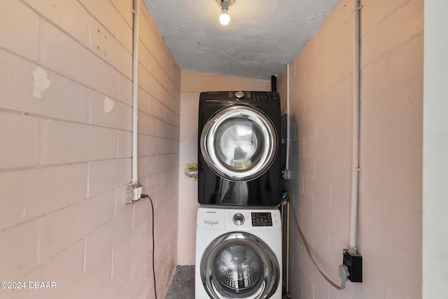 clothes washing area with a textured ceiling and stacked washer and clothes dryer