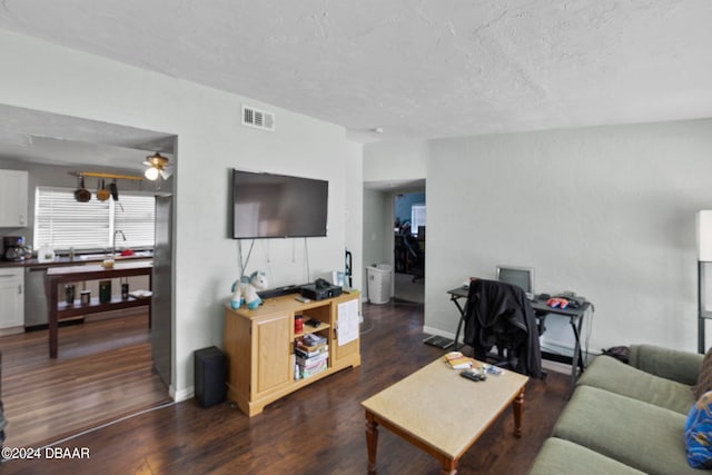 living room with dark hardwood / wood-style flooring, a textured ceiling, and ceiling fan