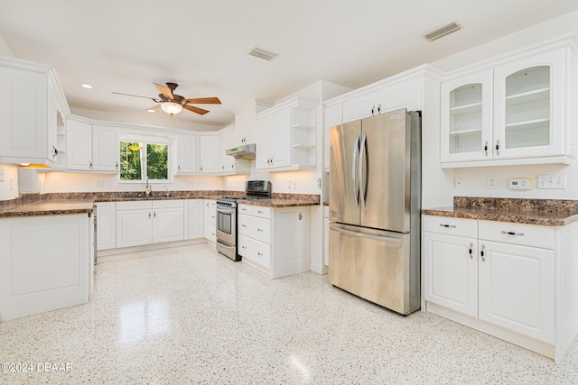 kitchen with sink, ceiling fan, dark stone countertops, appliances with stainless steel finishes, and white cabinetry