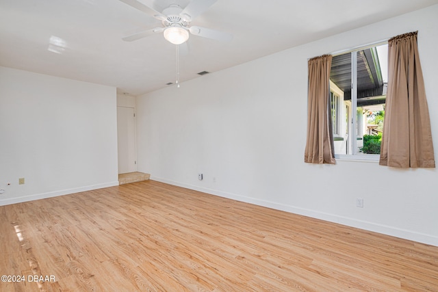 empty room with ceiling fan and light hardwood / wood-style flooring