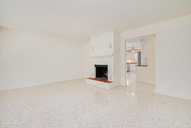 unfurnished living room featuring ceiling fan and a fireplace