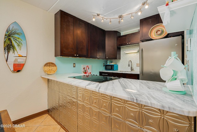 kitchen with sink, tasteful backsplash, black appliances, light stone countertops, and light tile patterned flooring