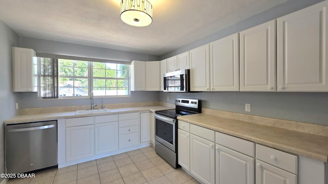 kitchen with stainless steel appliances, light countertops, white cabinets, and a sink