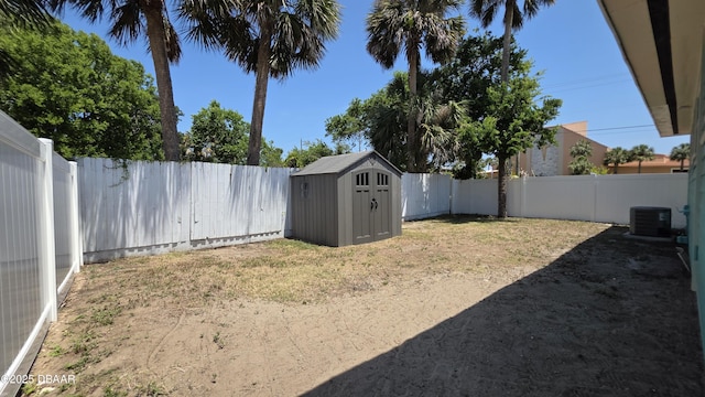 view of yard featuring a fenced backyard, a shed, central AC unit, and an outdoor structure