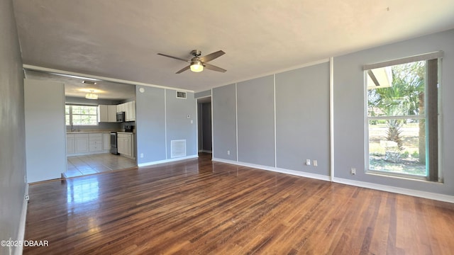 unfurnished living room featuring wood finished floors, a ceiling fan, visible vents, and baseboards