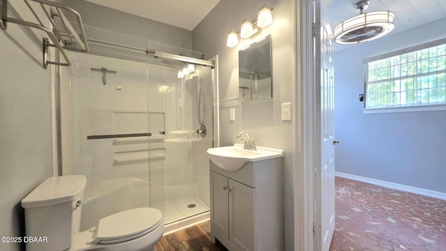 bathroom featuring baseboards, a stall shower, toilet, and vanity
