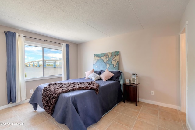 bedroom with baseboards, a textured ceiling, and light tile patterned flooring