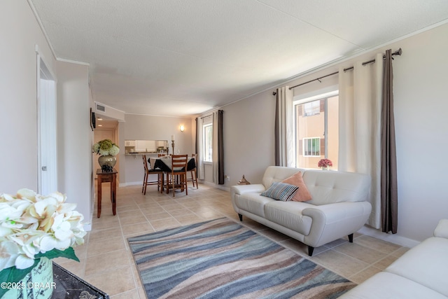 living room featuring light tile patterned floors, ornamental molding, visible vents, and baseboards