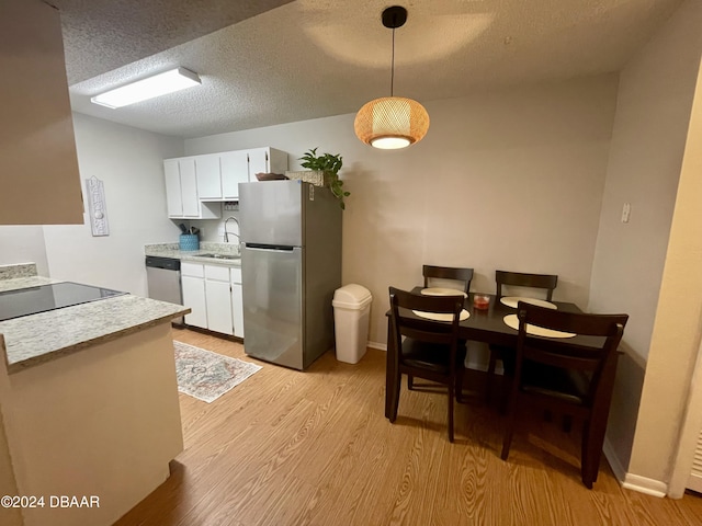 kitchen with pendant lighting, white cabinets, stainless steel appliances, and sink