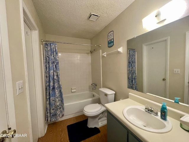 full bathroom with hardwood / wood-style floors, shower / bath combination with curtain, a textured ceiling, toilet, and vanity