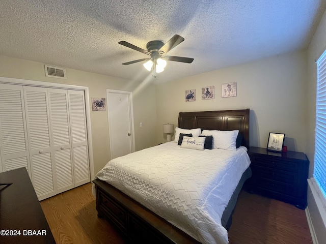 bedroom with ceiling fan, dark hardwood / wood-style floors, a textured ceiling, and a closet