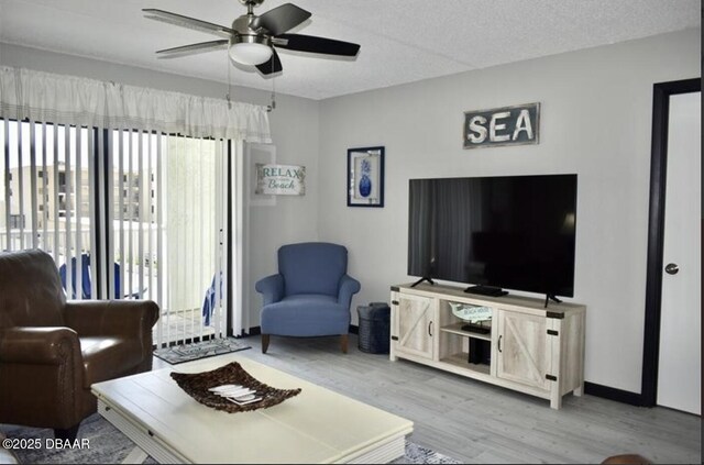 living room featuring ceiling fan, a textured ceiling, and light wood-type flooring