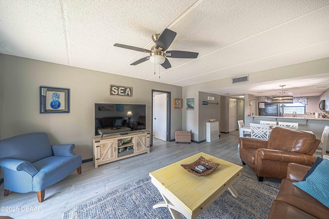3800 S Atlantic Ave Unit 3030, Daytona Beach, FL 32118 - living room featuring wood finished floors, a textured ceiling, ceiling fan, a chandelier, and baseboards