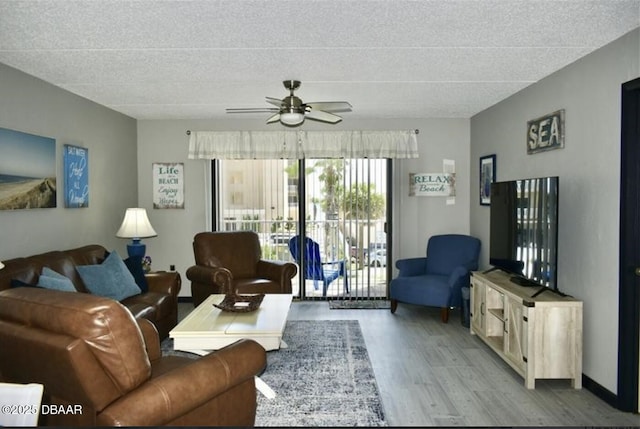 living room featuring ceiling fan, light hardwood / wood-style floors, and a textured ceiling