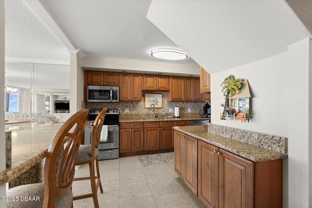 901 S Atlantic Ave Unit 202, Ormond Beach, FL 32176 - kitchen featuring appliances with stainless steel finishes, brown cabinets, backsplash, light stone counters, and light tile patterned flooring