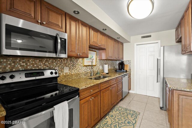 901 S Atlantic Ave Unit 202, Ormond Beach, FL 32176 - kitchen with stainless steel appliances, tasteful backsplash, brown cabinets, and light stone countertops
