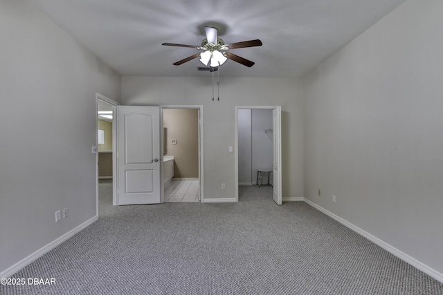 unfurnished bedroom with light carpet, ensuite bath, a walk in closet, and ceiling fan