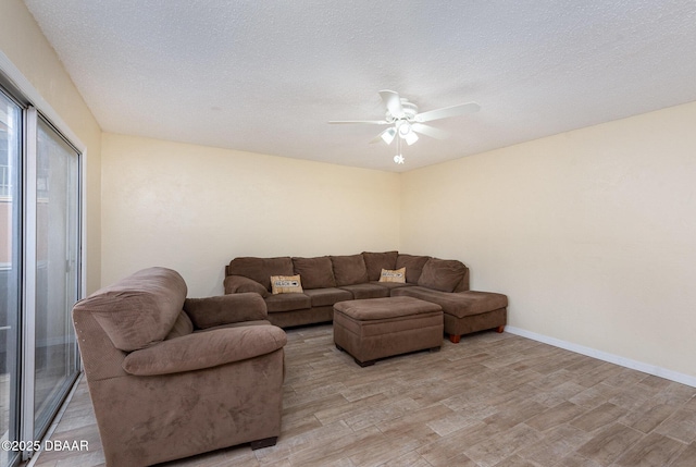 living room with ceiling fan, a textured ceiling, and light hardwood / wood-style flooring