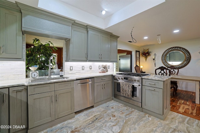 kitchen with kitchen peninsula, appliances with stainless steel finishes, sink, and light stone counters